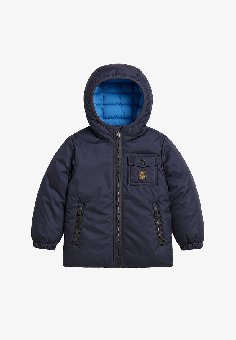Giacca imbottita con cappuccio di colore blu navy, foderata con un leggero blu quilted, con zip frontale, due tasche con zip e una tasca sul petto con bottone e patch.