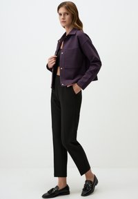 Paarse cropped jack met een kraag en voorzakken, gecombineerd met zwarte broeken en zwarte instappers, met een modern, Tailored ontwerp.