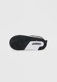 Talpa de adidași alb-negru cu cauciuc texturat, model de profil circular și logo-ul "JORDAN" în negru pe fundal alb.