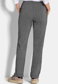 Grijze broek met visgraatpatroon, met een recht model en een elastische tailleband, gecombineerd met lichtgekleurde sneakers met een gestructureerd oppervlak.