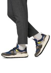 Multicolored sneakers featuring blue, gray, and yellow hues; textured suede and mesh materials; speckled white sole; and patterned detailing.