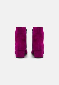 Magenta mocka anklar stövlar med klack, med en sidodragkedja och en smidig yta. Sulan är svart med minimal mönstring.