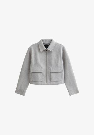 Chaqueta gris corta con cuello tipo solapa, cierre frontal de cremallera y dos grandes bolsillos delanteros. Confeccionada en una tela suave con un acabado ligeramente texturizado.