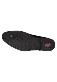 Suela de zapato negra con un patrón texturizado que presenta un logo circular con acentos rojos y azules. Bordes lisos y diseño de punta redondeada.
