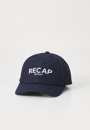 Marineblå baseballcaps laget av denimstoff. Har hvit broderte tekst "RECAP" og "REPEAT" på forsiden. Buet visirdesign.