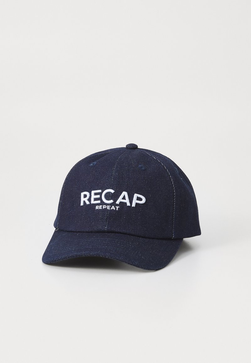 Marineblaue Baseballmütze aus Denimstoff. Mit weißen gestickten Texten "RECAP" und "REPEAT" auf der Vorderseite. Geformtes Schirmdesign.