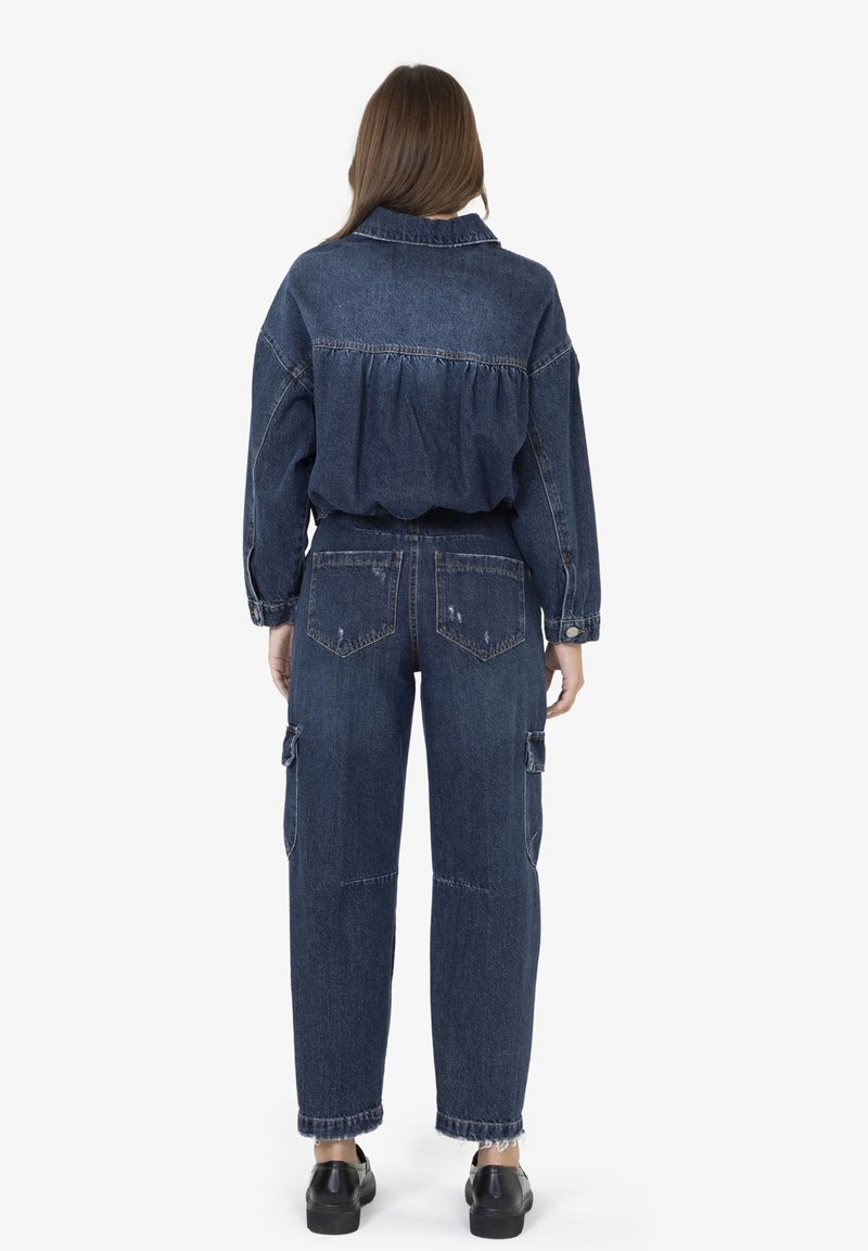 Spijkerjack met geplooide rug en losse pasvorm, gecombineerd met high-waisted cargo jeans met voorzakken en verwerkte details.