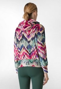 Felpa con zip colorata caratterizzata da un motivo a zig zag in tonalità di rosa, viola e verde, con cappuccio e polsini a costine. Realizzata in un tessuto morbido.