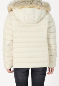 Lyse beige dunjakke med aftagelig hætte i imiteret pels, med vandrette quiltede segmenter og lange ærmer. Set fra bagsiden.