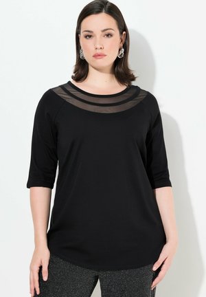 Zwarte top met driekwartmouwen, met een doorzichtige meshdraperie bij de halslijn. Soepele stof met een relaxed fit, gecombineerd met gestructureerde grijze broek.
