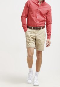 Rothe Hemd, beige Shorts, brauner Gürtel, weiße Sneakers und weiße Socken. Lässiges Outfit mit bequemer Passform und schlichtem Design.