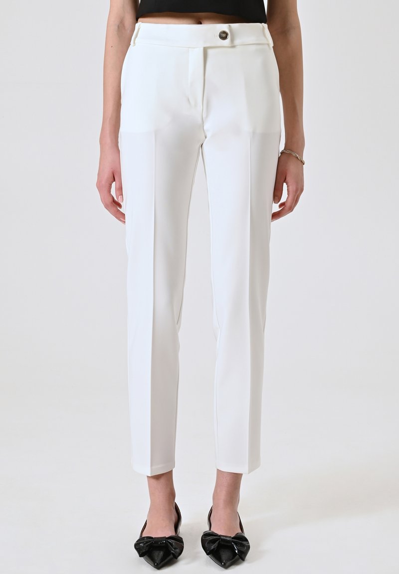 Pantalons blancs ajustés avec une coupe slim, poches latérales et une fermeture à bouton unique à la taille. Tissu lisse avec un détail de pli.