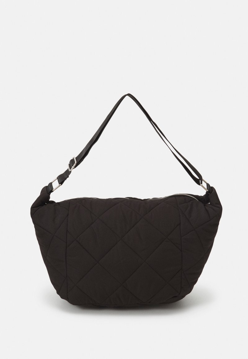 Sac à épaule en tissu noir matelassé avec bandoulière réglable et fermeture éclair sur le dessus, sur un fond clair uni.