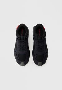 Pantofi sport negri cu un superior din plasă, guler căptușit și șireturi negre. O etichetă roșie pe călcâi și o talpă din cauciuc texturată.