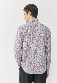 Košela s dlhým rukávom z ľahkej látky, so kvetinovým vzorom v odtieňoch ružovej, zelenej a bielej. Klasický golier a zaoblený lem.