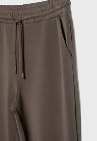 Bruine joggings met een elastische tailleband, verstelbare trekkoord en zijzakken. Glad oppervlak met een minimalistisch ontwerp.