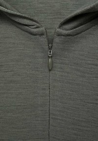 Sivi dukserica na zatvarač od teksturirane tkanine. Ima prednji zatvarač i minimalistički dizajn, koji prikazuje glatki, ravnomjerni pleteni uzorak.