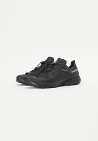 Chaussures de trail running noires avec un dessus texturé, des panneaux en mesh flexibles et une languette à l'arrière. Elles disposent d'un système de laçage rapide et d'une semelle robuste.