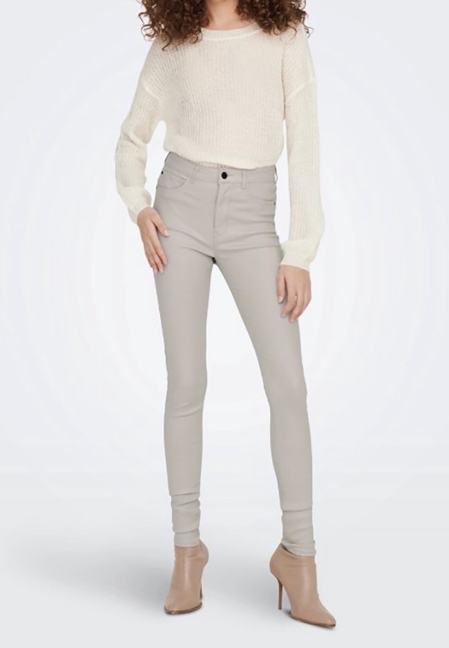 Crème gebreide trui, aansluitende lichtgrijze high-waisted jeans en beige haklaarsjes. Soepele textuur met subtiele rek.