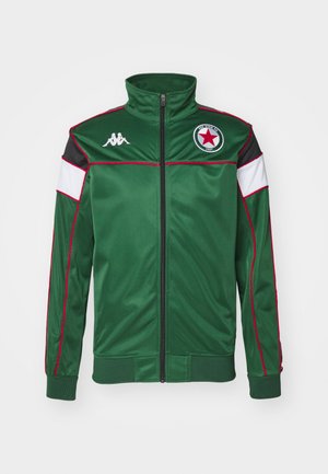 Veste de sport verte en tissu lisse. Dotée d'un col haut, d'une fermeture éclair intégrale, de panneaux en noir et blanc, d'accents rouges et d'un logo en forme d'étoile.