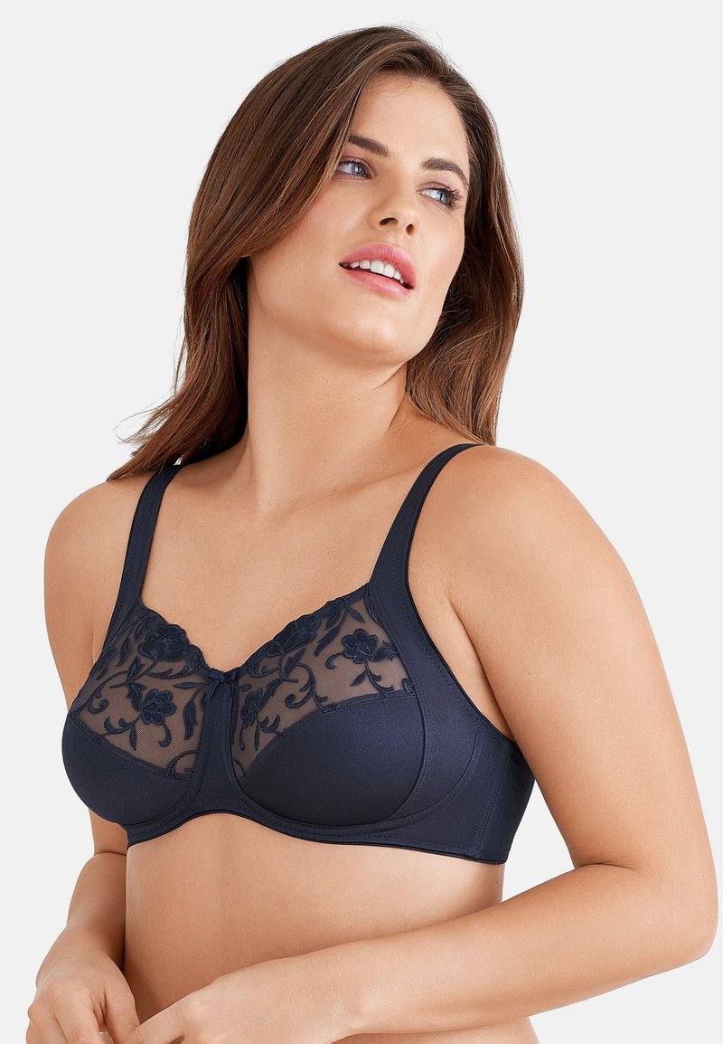 Granatowy biustonosz z przezroczystymi panelami ozdobionymi kwiatowym haftem, szerokimi ramiączkami oraz wyprofilowanym drutem podtrzymującym. Miękki materiał o gładkiej fakturze.