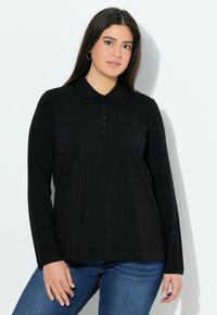 Černé polo tričko s dlouhým rukávem a límečkem, s légou na knoflíky a volným střihem, spárováno s modrými džíny.