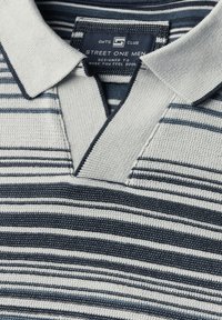 Pruhovaná polo košile s texturovaným pletením v šedé a námořnické modré barvě, s klasickým límcem a designem do V. Značková etiketa viditelná uvnitř límce.