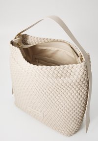 Woven beige leather handbag with a sturdy shoulder strap, gold-tone hardware, and a spacious interior featuring zippered compartments.