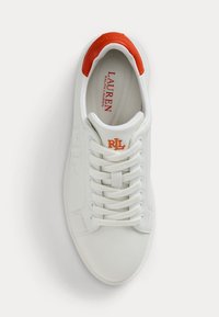 Hvit sneakers med en glatt skinn overdel og oransje detaljer på hælen. Har matchende lisser og såle av teksturert gummi.