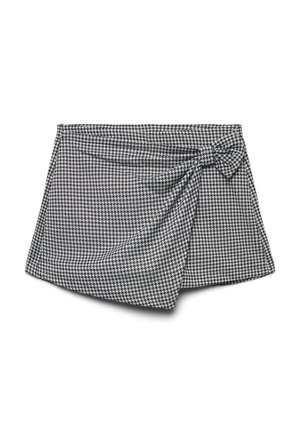 Gonna avvolgente in bianco e nero con motivo houndstooth, dettaglio con nodo laterale e morbida texture del tessuto; l'orlo asimmetrico aggiunge interesse visivo.
