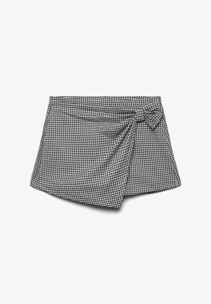 Gonna avvolgente in bianco e nero con motivo houndstooth, dettaglio con nodo laterale e morbida texture del tessuto; l'orlo asimmetrico aggiunge interesse visivo.