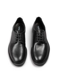 Scarpe in pelle nera con una finitura liscia, cinque occhielli per i lacci, punta arrotondata e suola in gomma a profilo basso. Branding sottile sulla soletta.