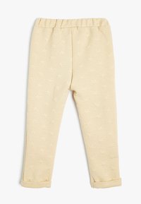 Helle beigefarbene Kinderhose mit einem elastischen Bund, ausgestattet mit einem strukturierten Sternmuster und umgeschlagenen Säumen an den Knöcheln.
