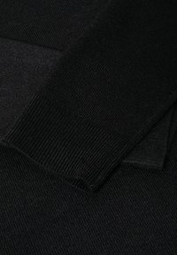 Schwarzer Strickstoff mit gerippter Textur, bei dem sich überlappende Abschnitte zu einem geschichteten Aussehen vereinen. Das Material ist leicht und glatt.
