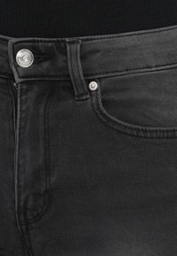 Μαύρο τζιν υφάσματος ντένιμ με ελαφριά υφή, διαθέτει ασημένια κουμπιά και κλασικό σχεδιασμό με πέντε τσέπες.