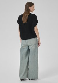 Black cropped knit sweater with short sleeves, paired with light blue wide-leg denim pants featuring a high waist and back pockets.