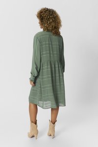 Blommig grön klänning med långa ärmar, texturerad tyg, rynkad midja och subtila horisontella ränder, som matchas med beige ankelskor.