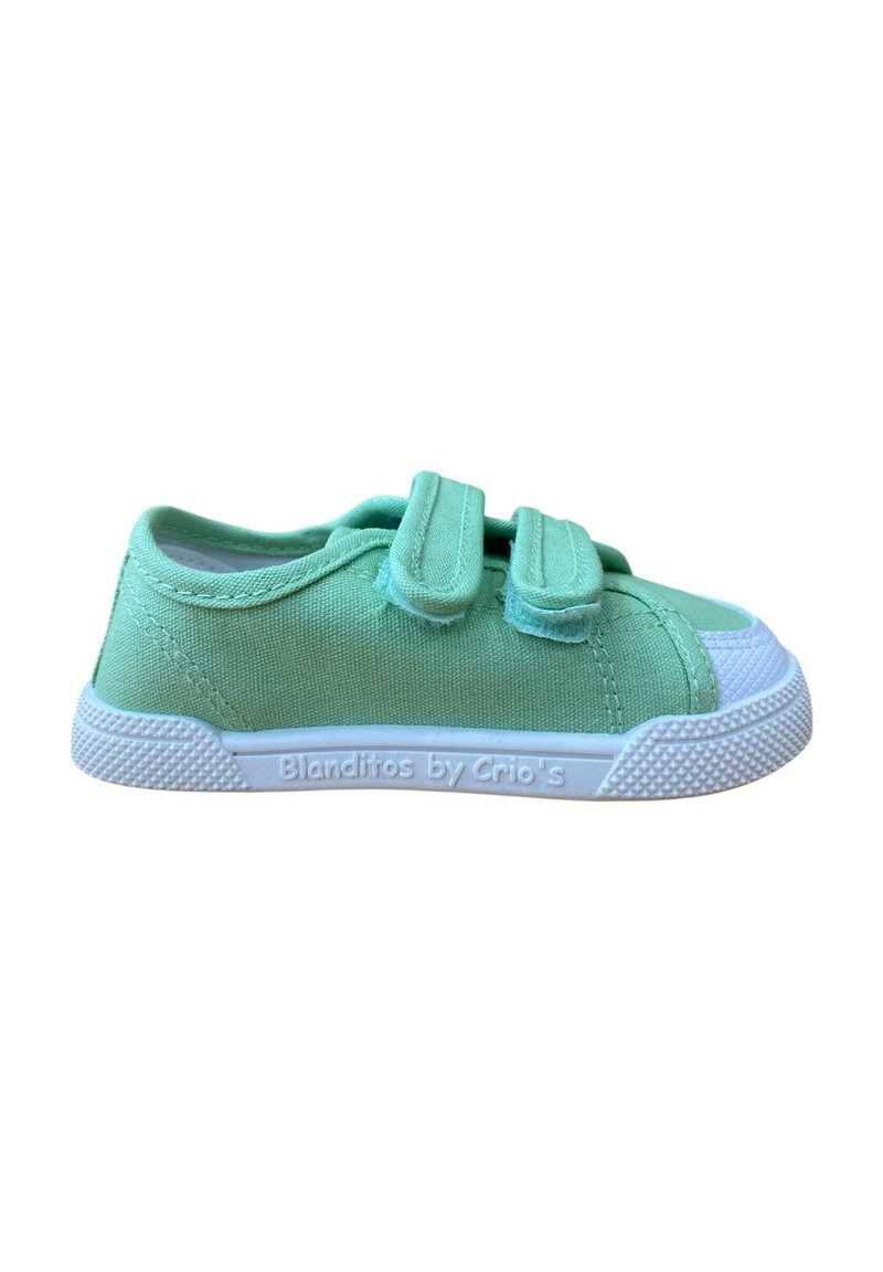Zapatilla de lona verde con dos tiras de Velcro, puntera de goma blanca y suela texturizada. Marca visible en el lateral, diseño minimalista.