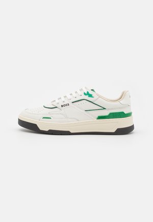 White sneaker with green accents, textured leather, perforated toe box, logo on the side, and a black rubber sole. Minimalist design.