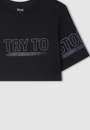 Czarny krótki t-shirt wykonany z bawełny, z krótkimi rękawami. Na przodzie i rękawie widnieje wyrazisty, odblaskowy napis "SPRÓBUJ MNIE ZATRZYMAĆ".