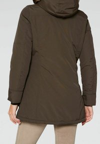 Brun isolerad jacka med huva, med en slät yta och elastiska manschetter. Baksidan har en något längre skärning för ökad täckning.