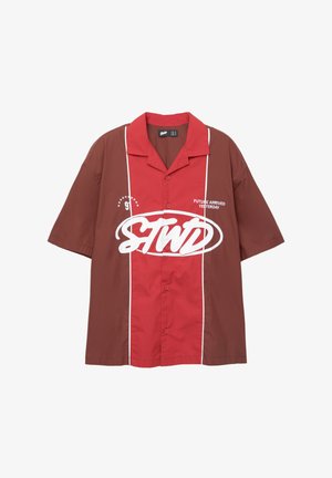 Kortærmet skjorte med et farveblokdesign i rød og brun. Har hvide kanter, forreste knapper og trykt tekst "FREMTIDEN ANKOM I GÅR."