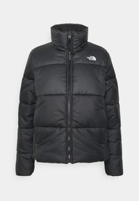 Chaqueta acolchada negra con cuello alto, que presenta una cremallera frontal y secciones acolchadas horizontales. El logo de The North Face está visible en el pecho.