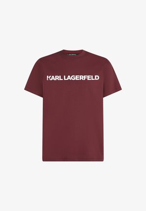 Tumepruun puuvillane T-särk lühikeste varrukatega ja ümmarguse kaelusega, mille rindkereosas on suurte valgete suurte tähtedega trükitud "KARL LAGERFELD".