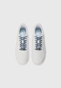 White sneakers with a smooth finish, perforated toe box, blue and black patterned laces, and a light blue insole featuring the Nike logo.