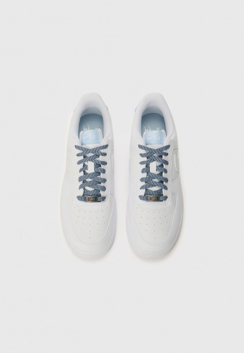 Białe trampki o gładkim wykończeniu, perforowanej części palców, niebiesko-czarne sznurówki w wzór oraz jasnoniebieska wkładka z logo Nike.