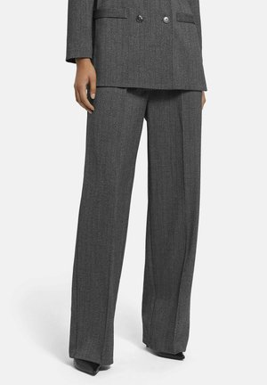 Graues Nadelstreifenanzug mit einem doppelt gefütterten Blazer und weit geschnittenen Hosen. Glatte Textur mit subtiler Glanzwirkung, ergänzt durch spitze Absatzschuhe.