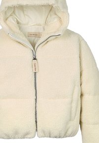 Kremowa polarowa kurtka z kapturem, z zamkiem z przodu i kieszeniami po bokach, z metką Calvin Klein na uchwycie zamka.
