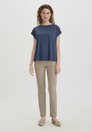Marineblauw T-shirt met korte mouwen en een losse fit, gecombineerd met beige slim-fit broeken en lichtbeige instap schoenen. Glad materiaal en eenvoudig ontwerp.