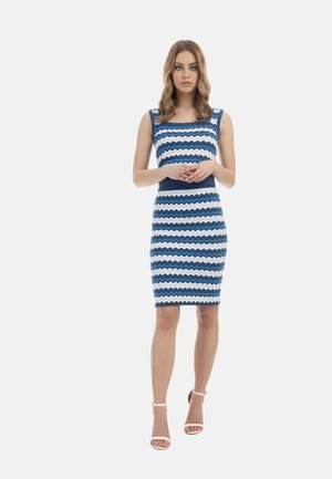 Rochie ajustată cu model în zig-zag albastru și alb, cu decolteu pătrat și bretele late. Modelul poartă sandale albe cu barete. Textură fină.